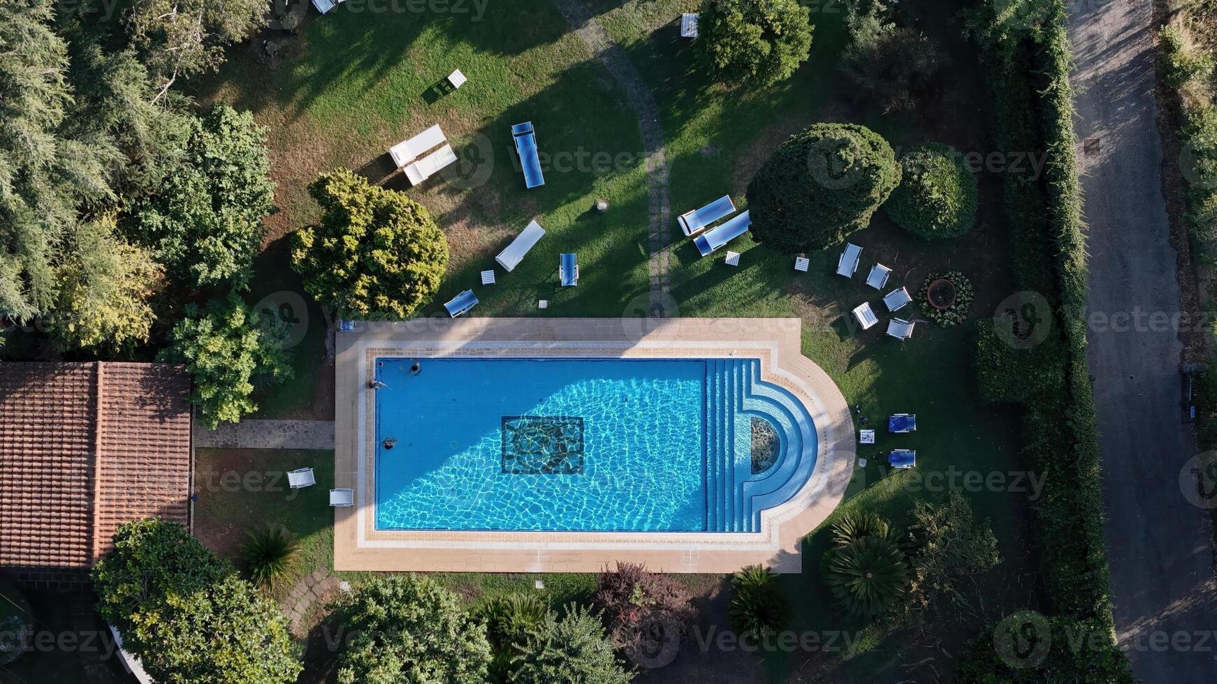 An aerial view of a serene swimming pool nestled in lush greenery, inviting relaxation under the midday sun photo