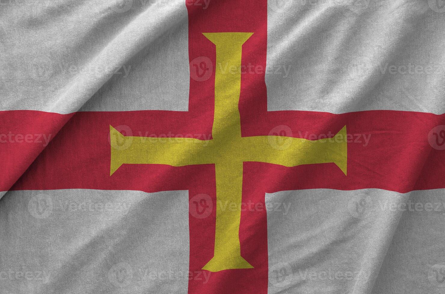 Guernsey flag depicted on folded wavy fabric of old cloth photo