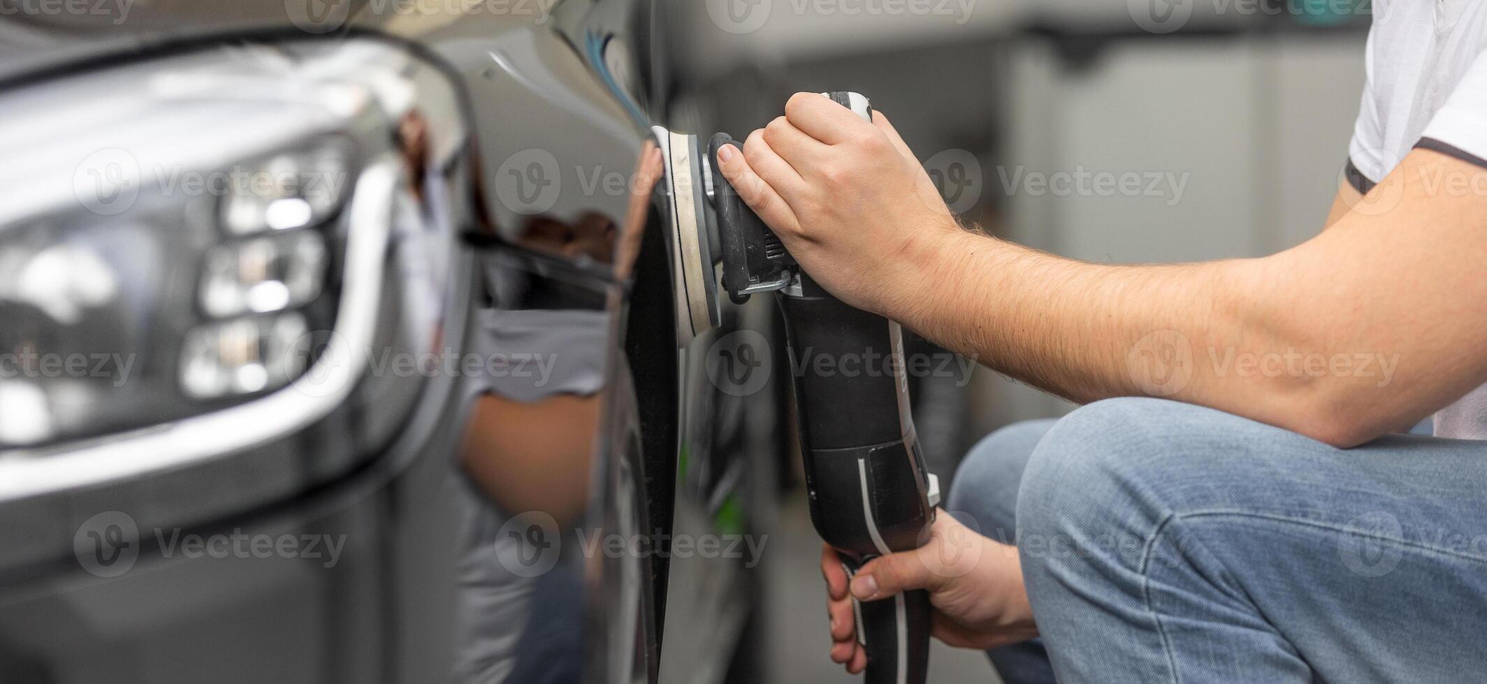 Professional detailing a car in car studio, hands with orbital polisher, scratching remover, vehicle care concept photo