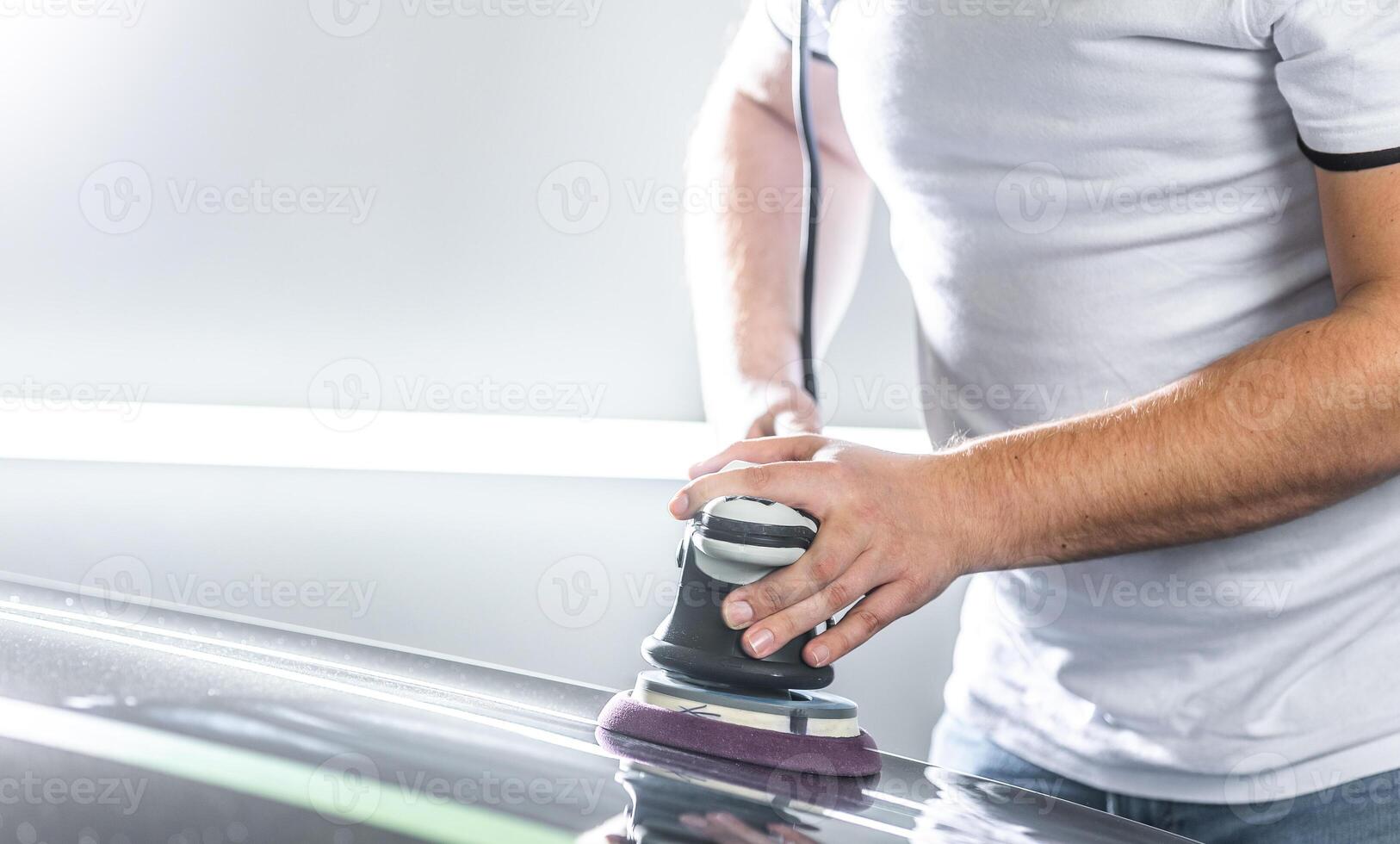 Detailing a cars concept, young man using orbital polisher for removing scratches from the car photo
