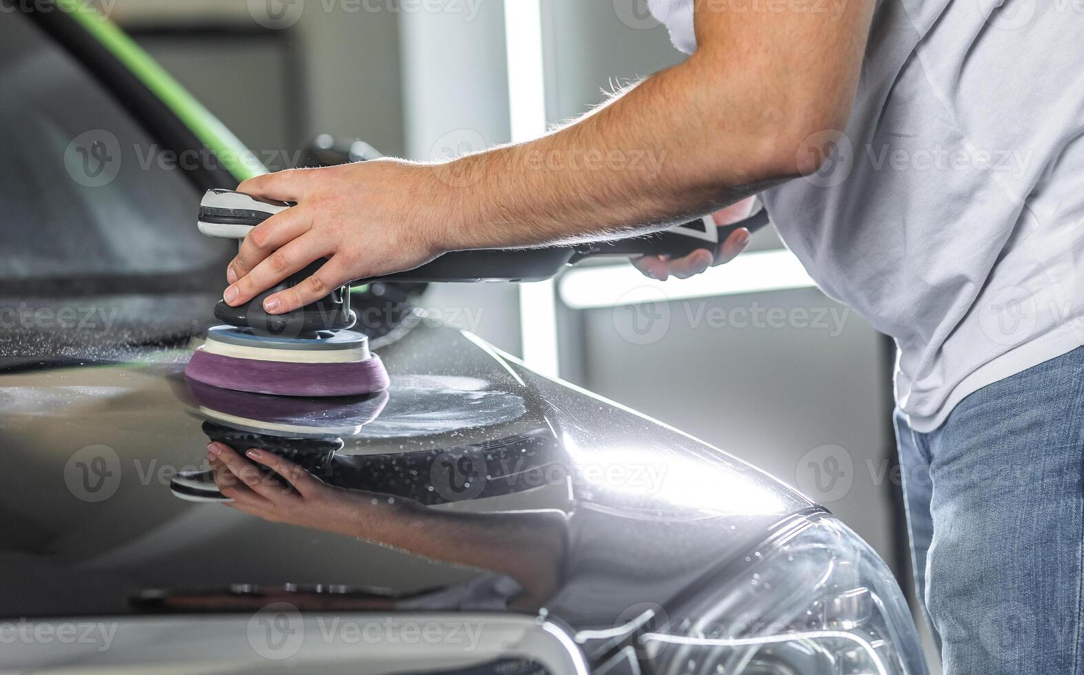 Young man polishing the hood of the car with an orbital polisher for removing scratches from the car, detailing concept photo