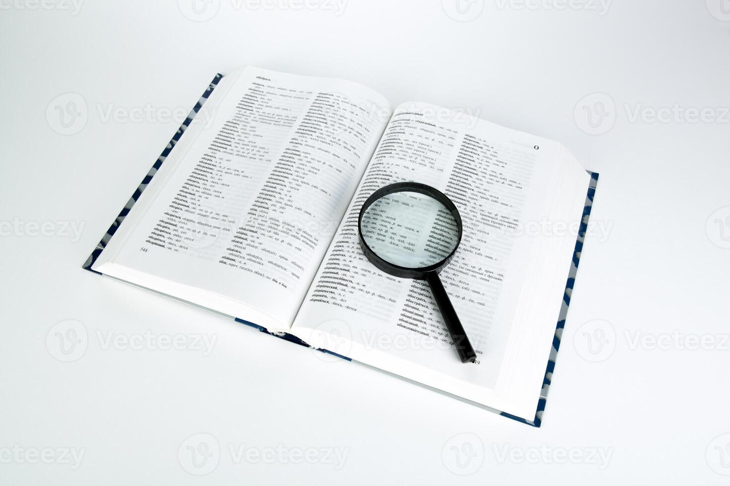 open book dictionary with loupe closeup photo