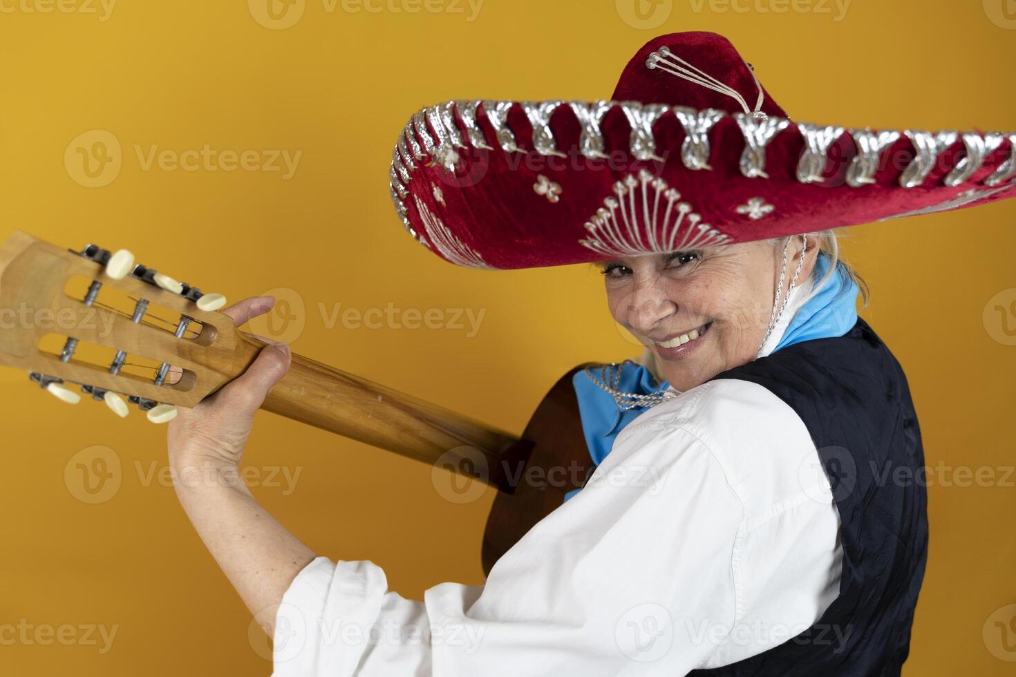 Funny portrait of mature woman. A lady playing the guitar dressed as a Mexican mariachi photo