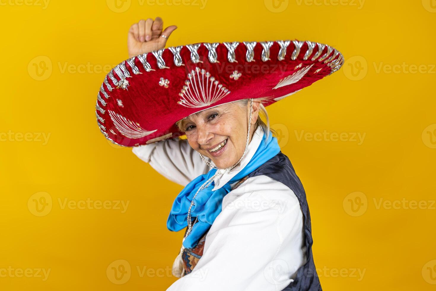 Funny portrait of mature woman. A lady with a sombrero dancing dressed as a Mexican mariachi photo