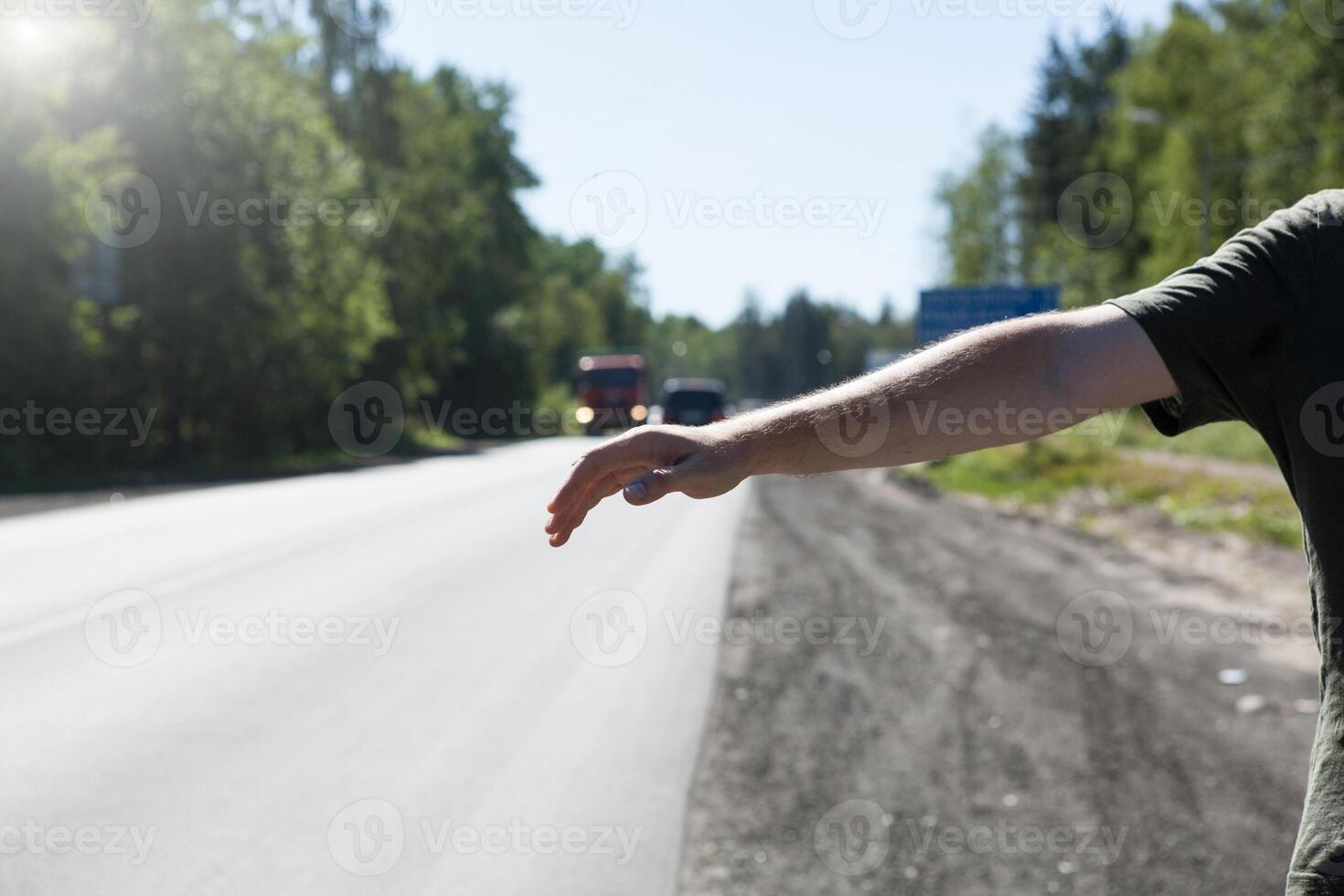 hand of a man is stretched out on the road with a hitchhiker photo
