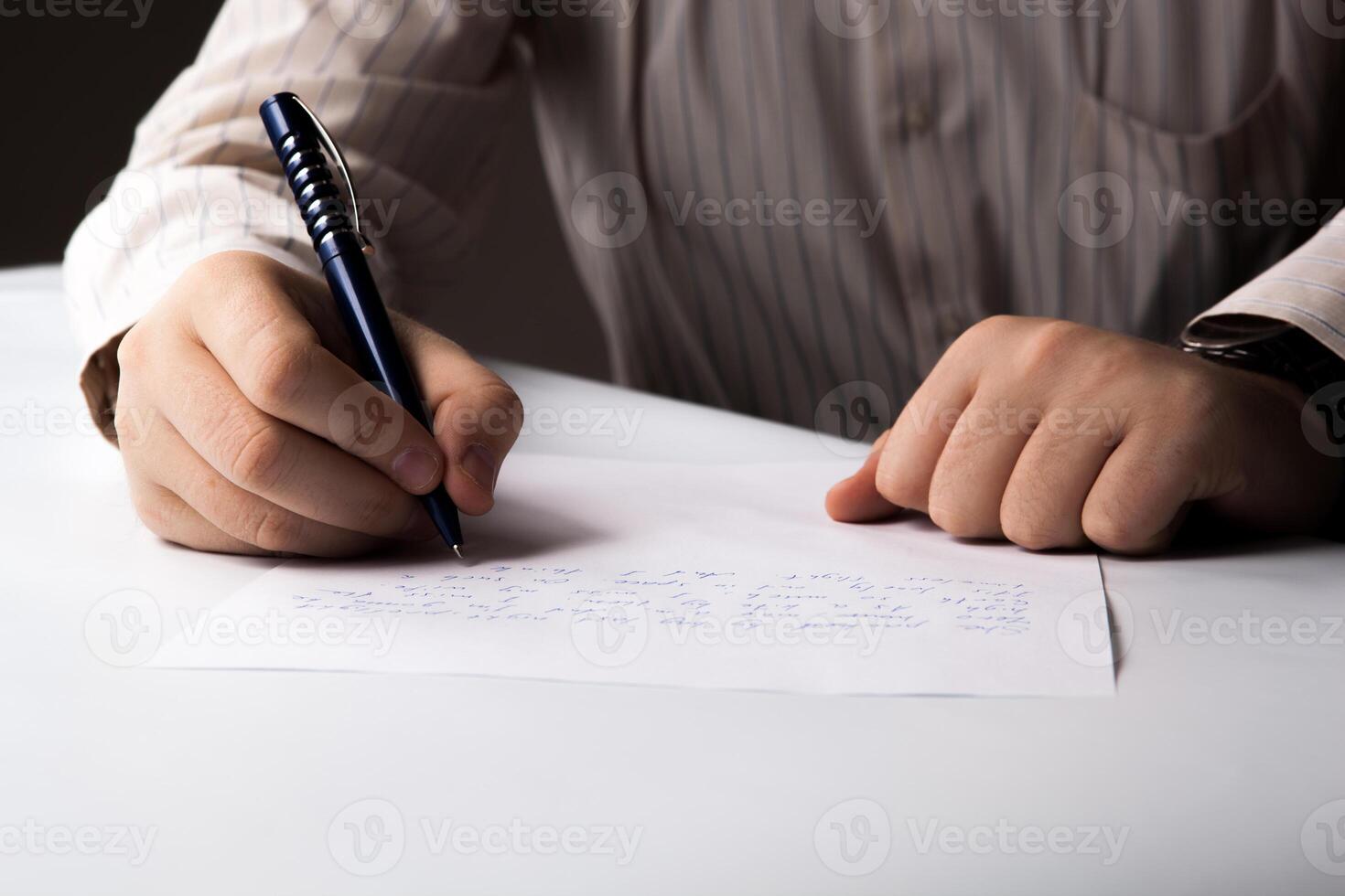 man is writting on a sheet of paper photo