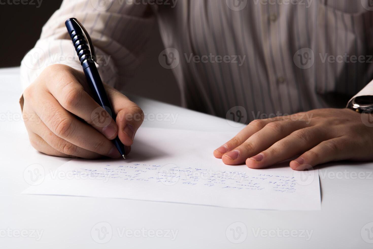 man is writting on a sheet of paper photo