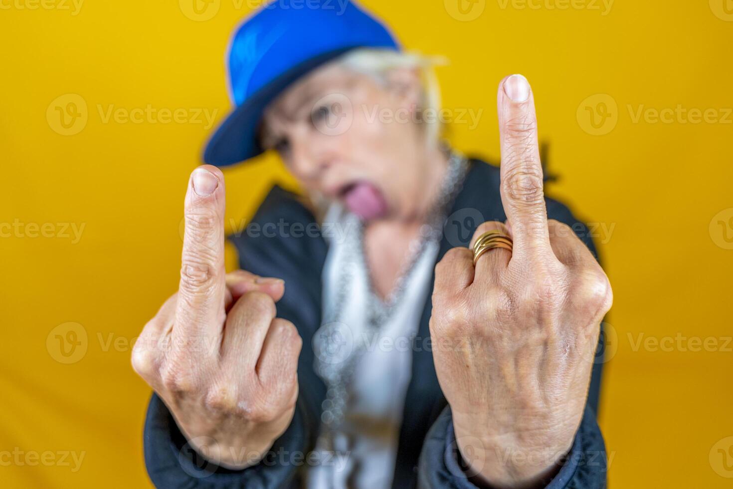 Funny portrait of mature woman. Lady shows the middle finger dressed as an angry rapper photo