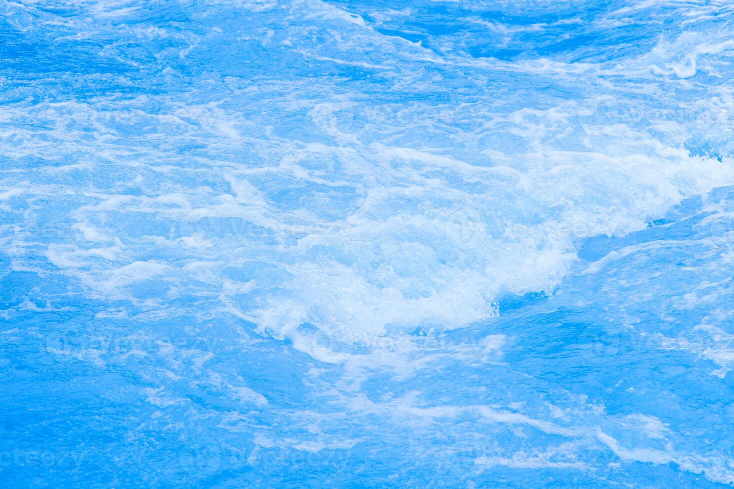 Bluewater waves on the surface ripples blurred. Defocus blurred transparent blue colored clear calm water surface texture with splash and bubbles. Water waves with shining pattern texture background. photo