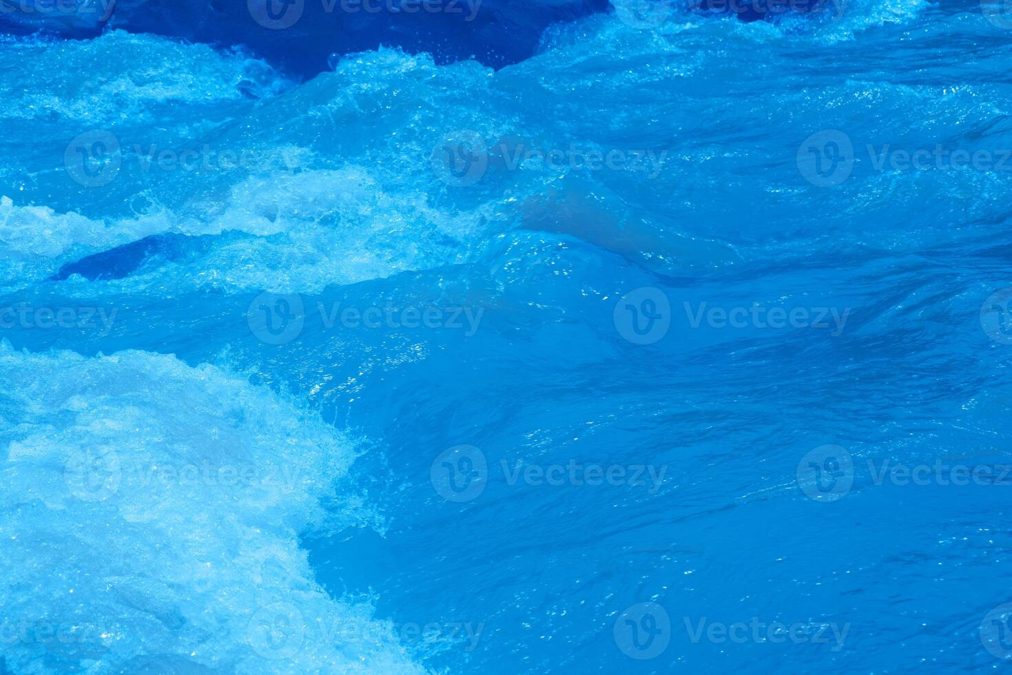 Bluewater waves on the surface ripples blurred. Defocus blurred transparent blue colored clear calm water surface texture with splash and bubbles. Water waves with shining pattern texture background. photo