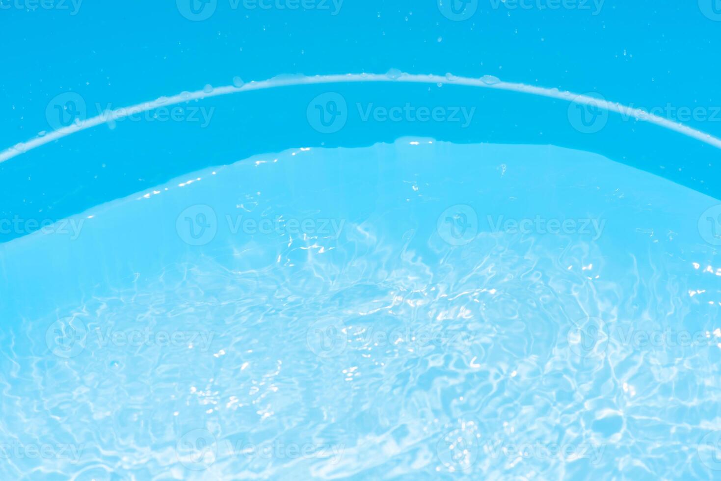 Bluewater waves on the surface ripples blurred. Defocus blurred transparent blue colored clear calm water surface texture with splash and bubbles. Water waves with shining pattern texture background. photo