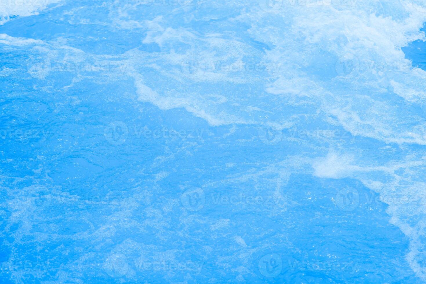 Bluewater waves on the surface ripples blurred. Defocus blurred transparent blue colored clear calm water surface texture with splash and bubbles. Water waves with shining pattern texture background. photo
