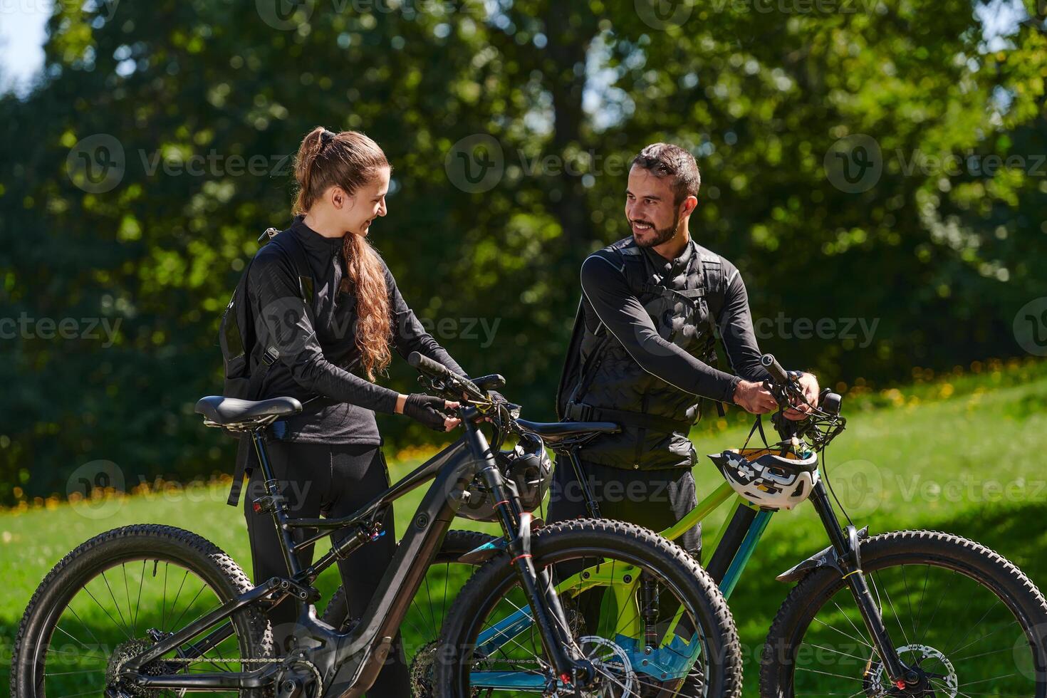A sweet couple, equipped with bicycles and engrossed in coordinating their journey, checks their GPS mobile and watches while planning scenic routes in the park, seamlessly blending technology and photo