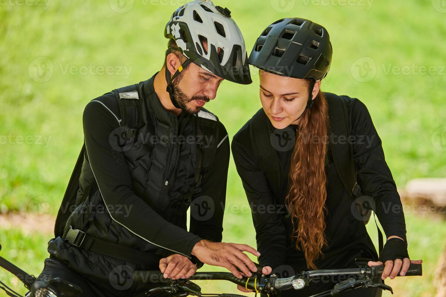 A blissful couple, adorned in professional cycling gear, enjoys a romantic bicycle ride through a park, surrounded by modern natural attractions, radiating love and happiness photo