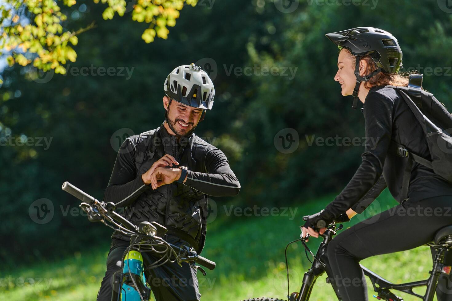 A sweet couple, equipped with bicycles and engrossed in coordinating their journey, checks their GPS mobile and watches while planning scenic routes in the park, seamlessly blending technology and photo