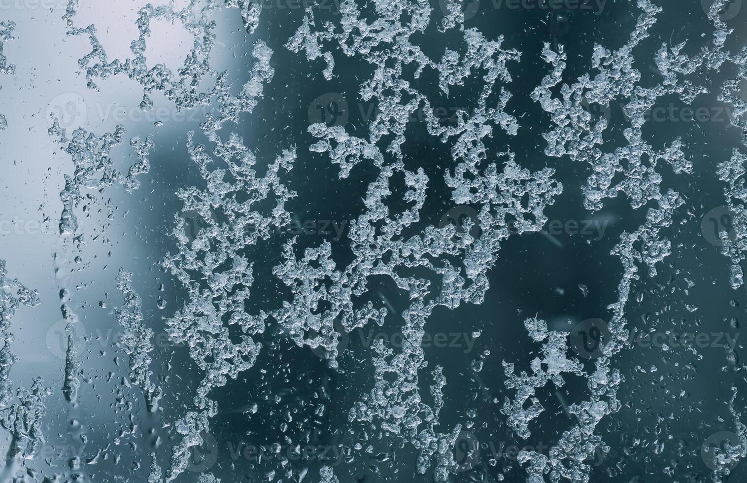 Frozen window glass with melting ice. Wet window background. photo