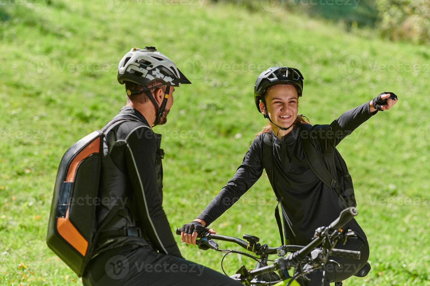 A sweet couple, equipped with bicycles and engrossed in coordinating their journey, checks their GPS mobile and watches while planning scenic routes in the park, seamlessly blending technology and photo