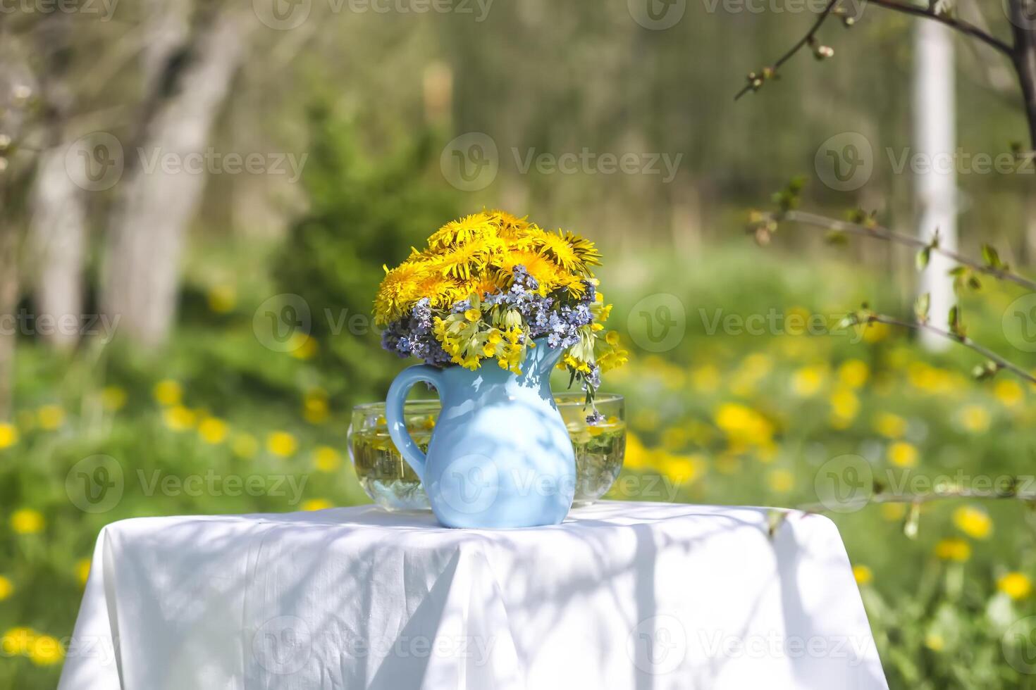 Dandelion flowers in the blue ceramic jug in sunlight. Floral composition outdoors. photo