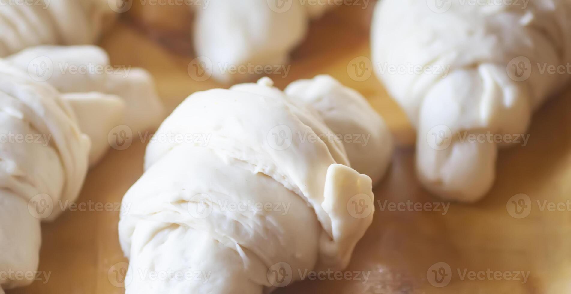 Raw croissant rolls in baking process. photo