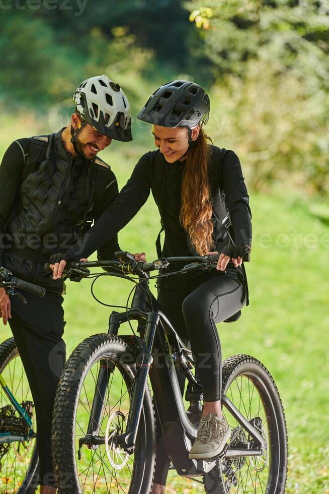 A sweet couple, equipped with bicycles and engrossed in coordinating their journey, checks their GPS mobile and watches while planning scenic routes in the park, seamlessly blending technology and photo