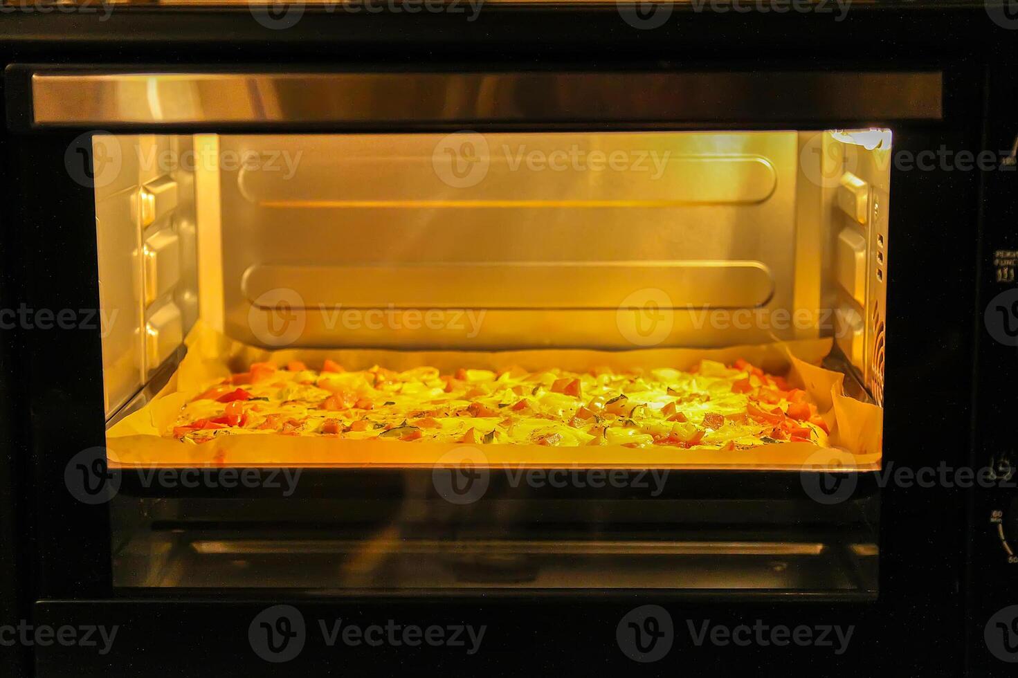 Pizza with tomatoes and meat baking in the oven photo