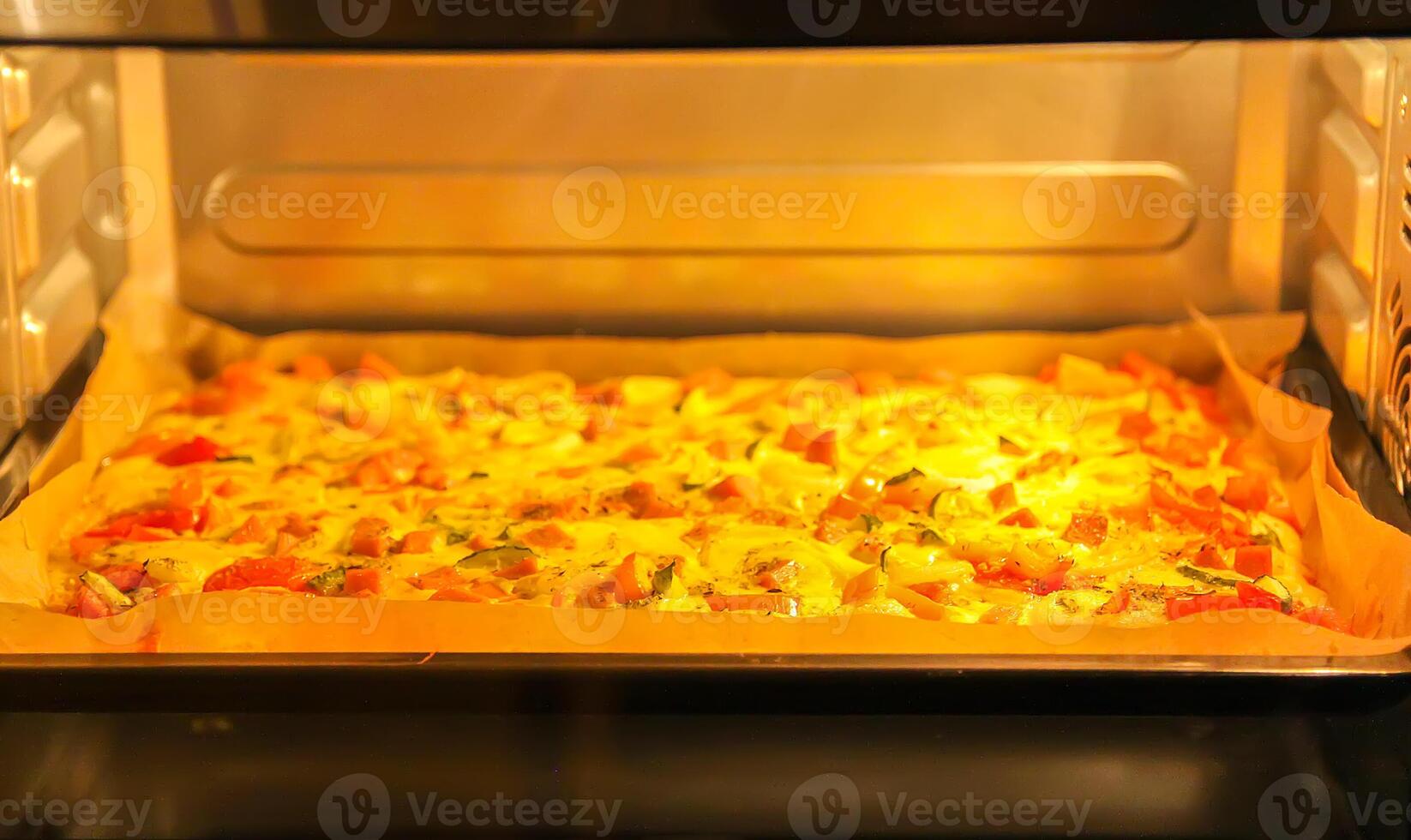 Pizza with tomatoes and meat baking in the oven photo