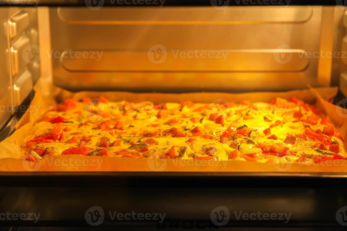 Pizza with tomatoes and meat baking in the oven photo
