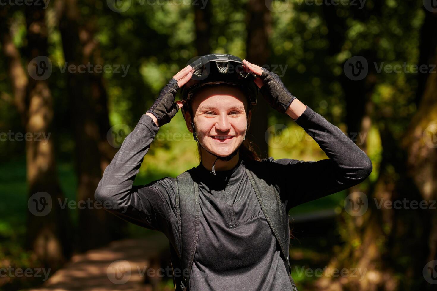 In the radiant embrace of a sunny day, a modern woman revels in the joy of cycling, her sleek bicycle and professional gear complementing her active lifestyle as she rides through the park photo