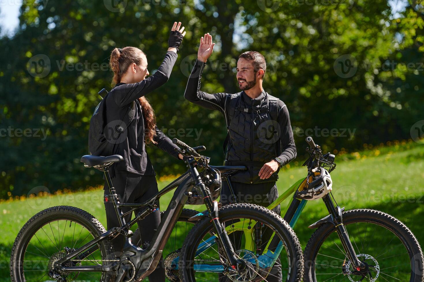 A sweet couple, equipped with bicycles and engrossed in coordinating their journey, checks their GPS mobile and watches while planning scenic routes in the park, seamlessly blending technology and photo