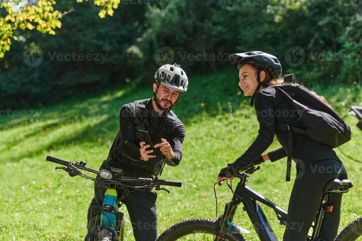 A sweet couple, equipped with bicycles and engrossed in coordinating their journey, checks their GPS mobile and watches while planning scenic routes in the park, seamlessly blending technology and photo