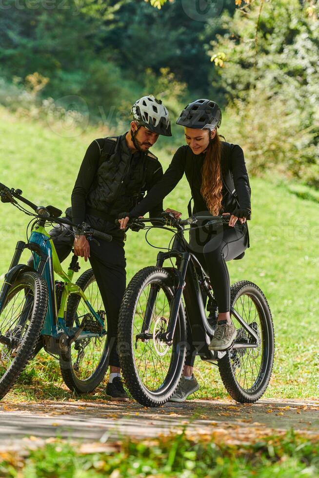 A sweet couple, equipped with bicycles and engrossed in coordinating their journey, checks their GPS mobile and watches while planning scenic routes in the park, seamlessly blending technology and photo