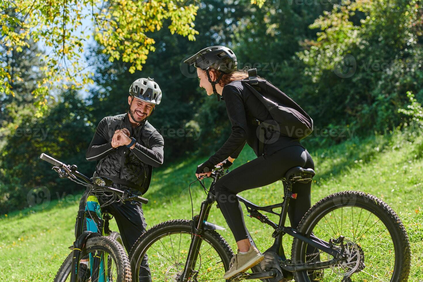 A sweet couple, equipped with bicycles and engrossed in coordinating their journey, checks their GPS mobile and watches while planning scenic routes in the park, seamlessly blending technology and photo