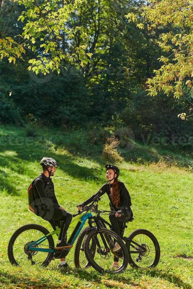 A sweet couple, equipped with bicycles and engrossed in coordinating their journey, checks their GPS mobile and watches while planning scenic routes in the park, seamlessly blending technology and photo