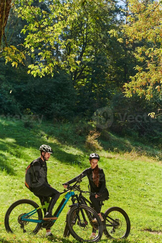 A sweet couple, equipped with bicycles and engrossed in coordinating their journey, checks their GPS mobile and watches while planning scenic routes in the park, seamlessly blending technology and photo
