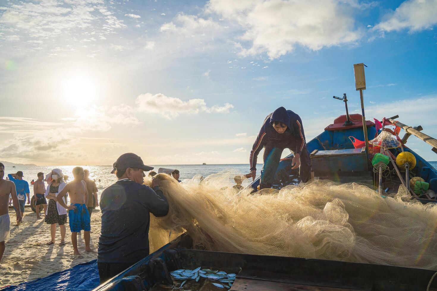 Vung Tau, VIETNAM - AUG 20 2022 Fisherman casting his net at the sunrise or sunset. Traditional fishermen prepare the fishing net. Fishermen on beach at the Fishing. photo