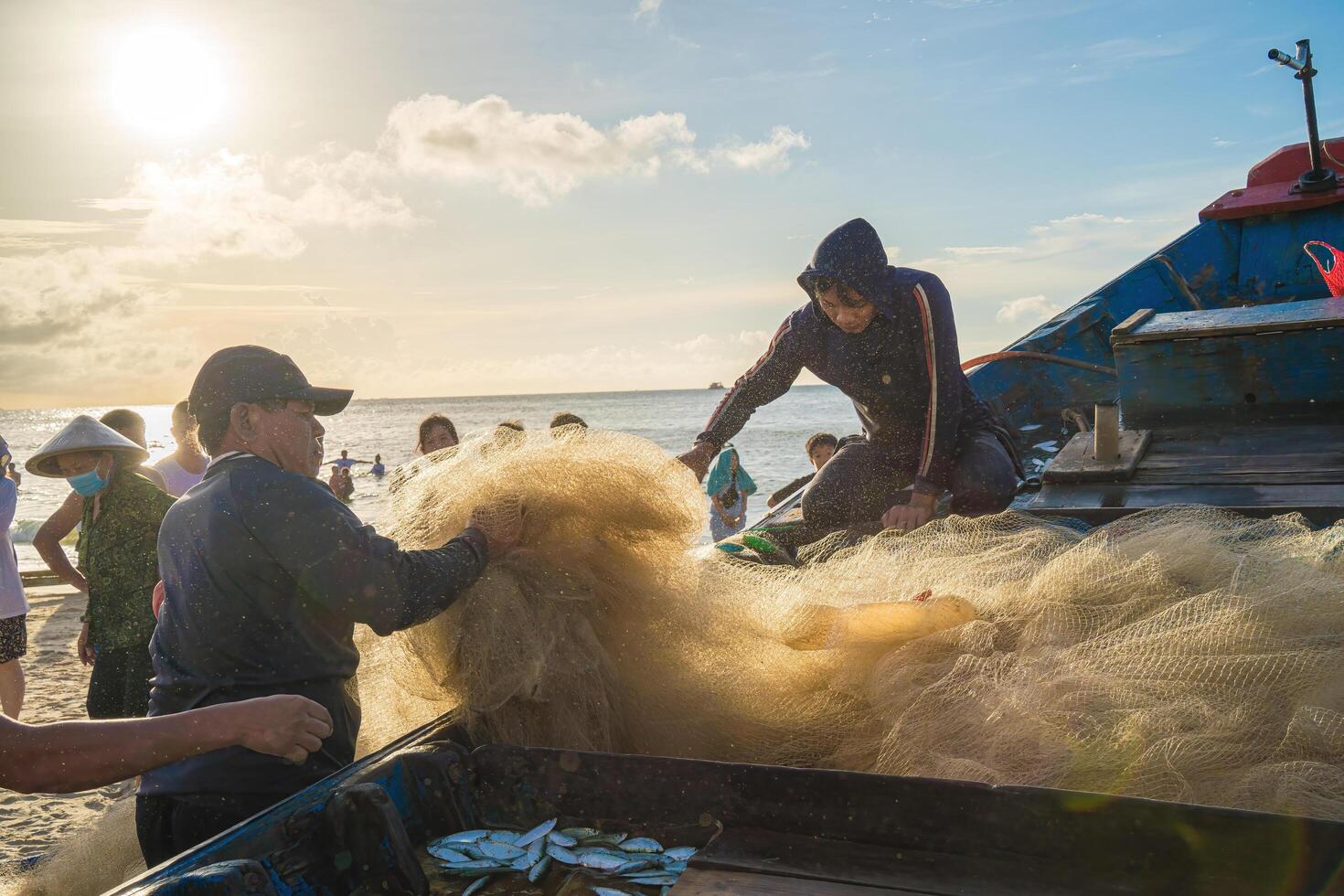 Vung Tau, VIETNAM - AUG 20 2022 Fisherman casting his net at the sunrise or sunset. Traditional fishermen prepare the fishing net. Fishermen on beach at the Fishing. photo