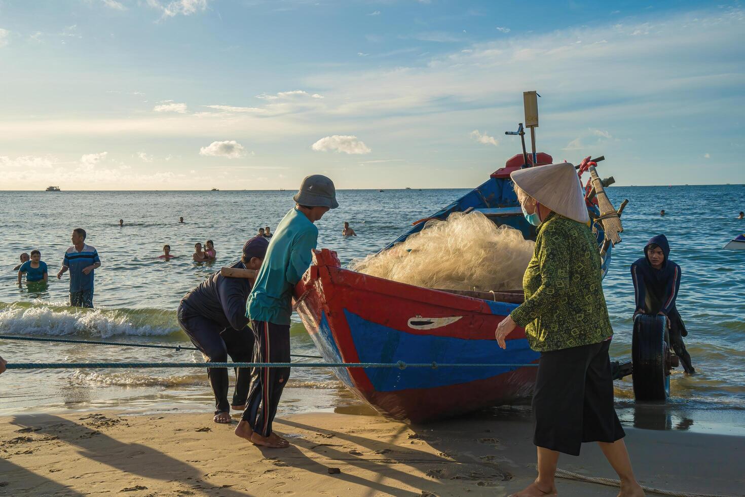 Vung Tau, VIETNAM - AUG 20 2022 Fisherman casting his net at the sunrise or sunset. Traditional fishermen prepare the fishing net. Fishermen on beach at the Fishing. photo