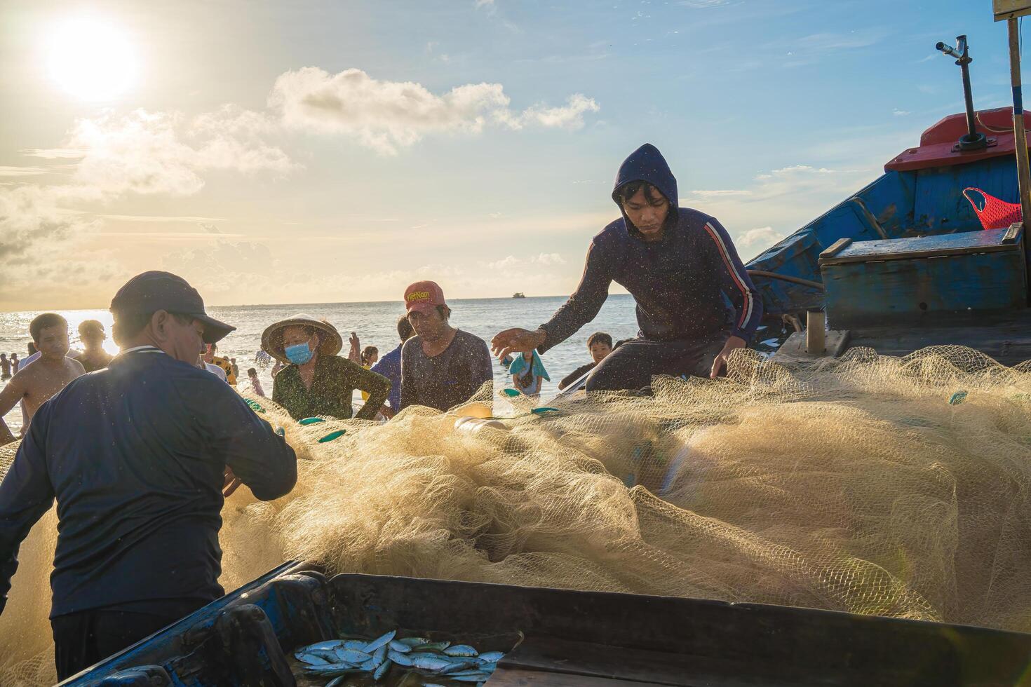 Vung Tau, VIETNAM - AUG 20 2022 Fisherman casting his net at the sunrise or sunset. Traditional fishermen prepare the fishing net. Fishermen on beach at the Fishing. photo
