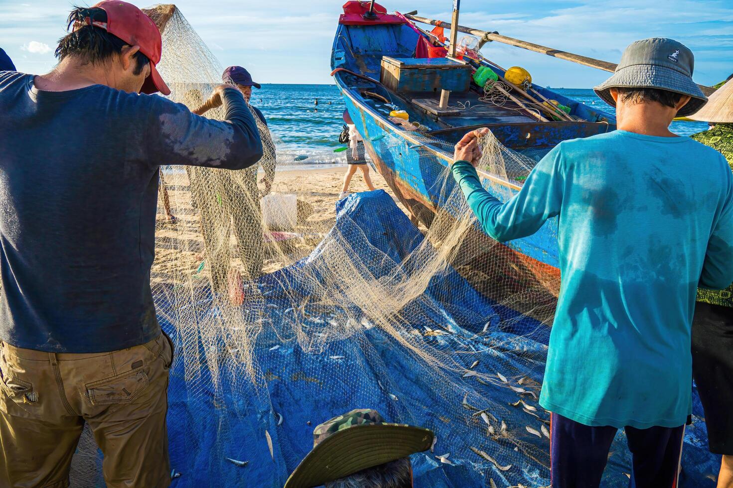 Vung Tau, VIETNAM - AUG 20 2022 Fisherman casting his net at the sunrise or sunset. Traditional fishermen prepare the fishing net. Fishermen on beach at the Fishing. photo
