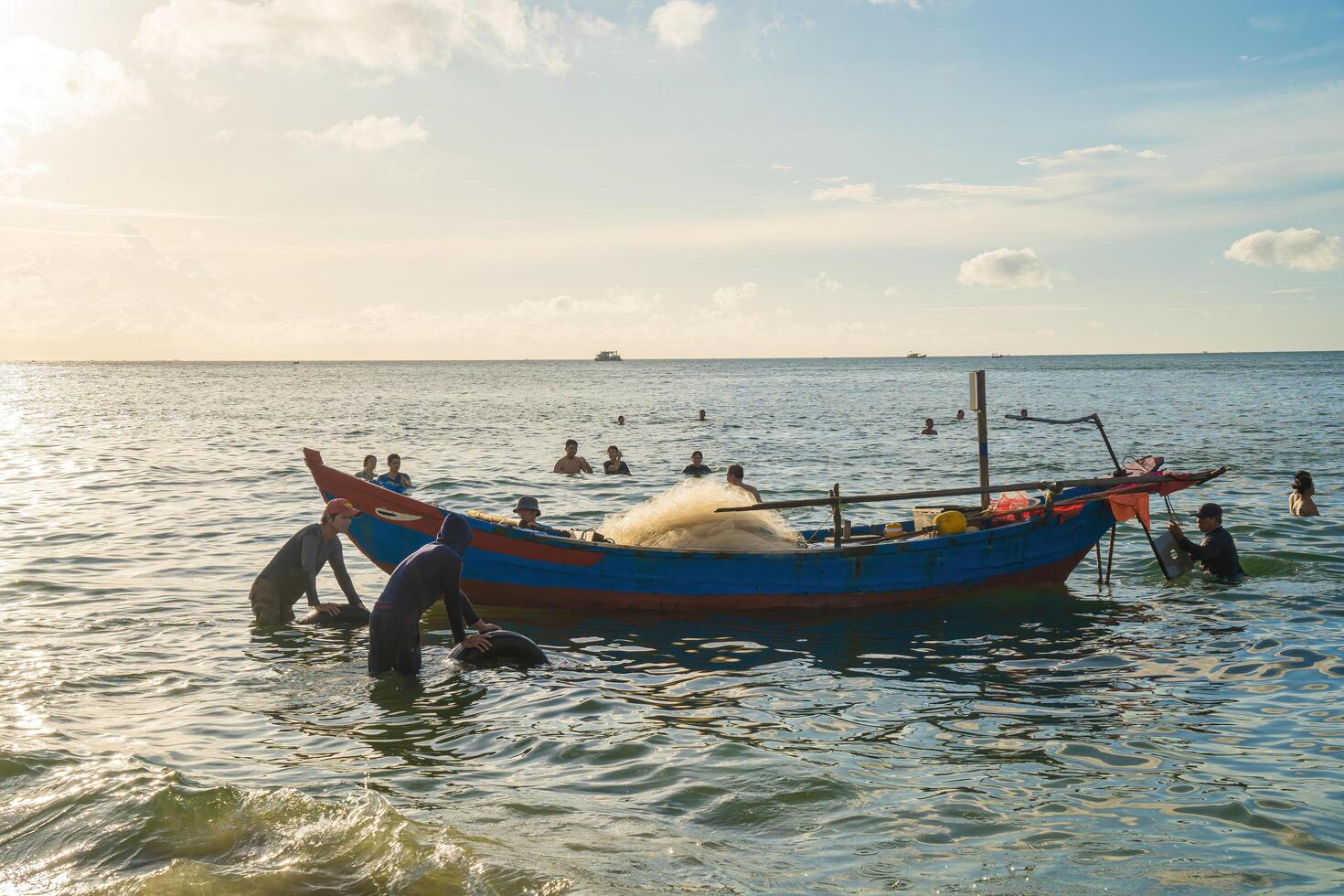 Vung Tau, VIETNAM - AUG 20 2022 Fisherman casting his net at the sunrise or sunset. Traditional fishermen prepare the fishing net. Fishermen on beach at the Fishing. photo