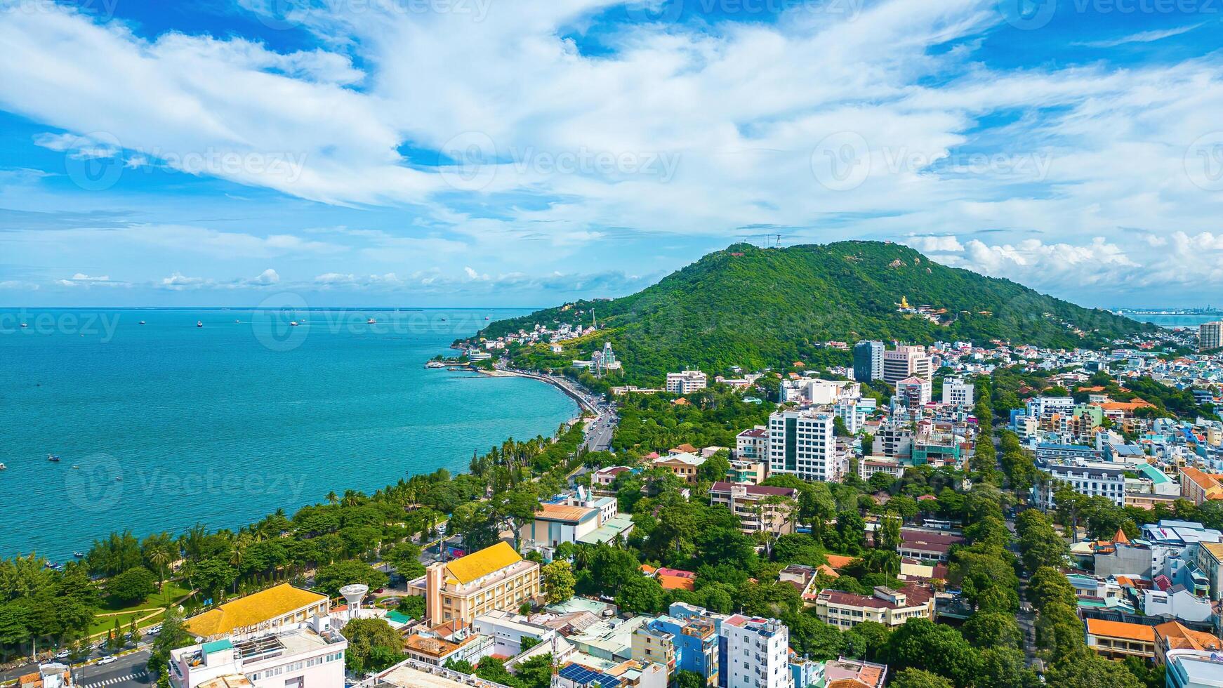 Vung Tau city aerial view with beautiful sunset and so many boats. Panoramic coastal Vung Tau view from above, with waves, coastline, streets, coconut trees and Tao Phung mountain in Vietnam. photo