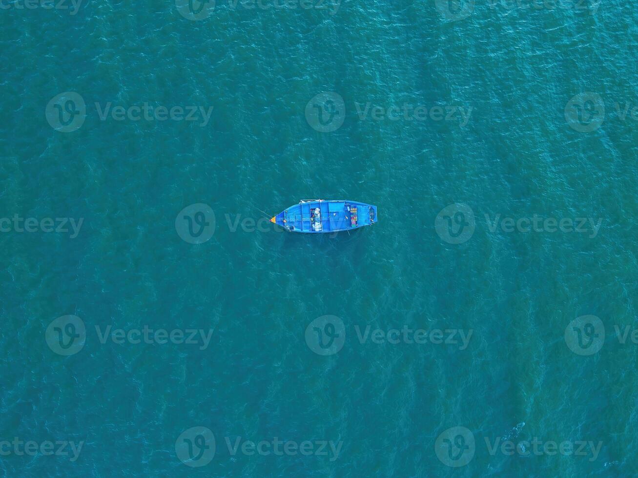Top view, aerial view wooden fishing boat on the beach from a drone. Royalty high quality stock photo image of the wooden fishing boat on the beach. Fishing boat is mooring on clear blue beach alone