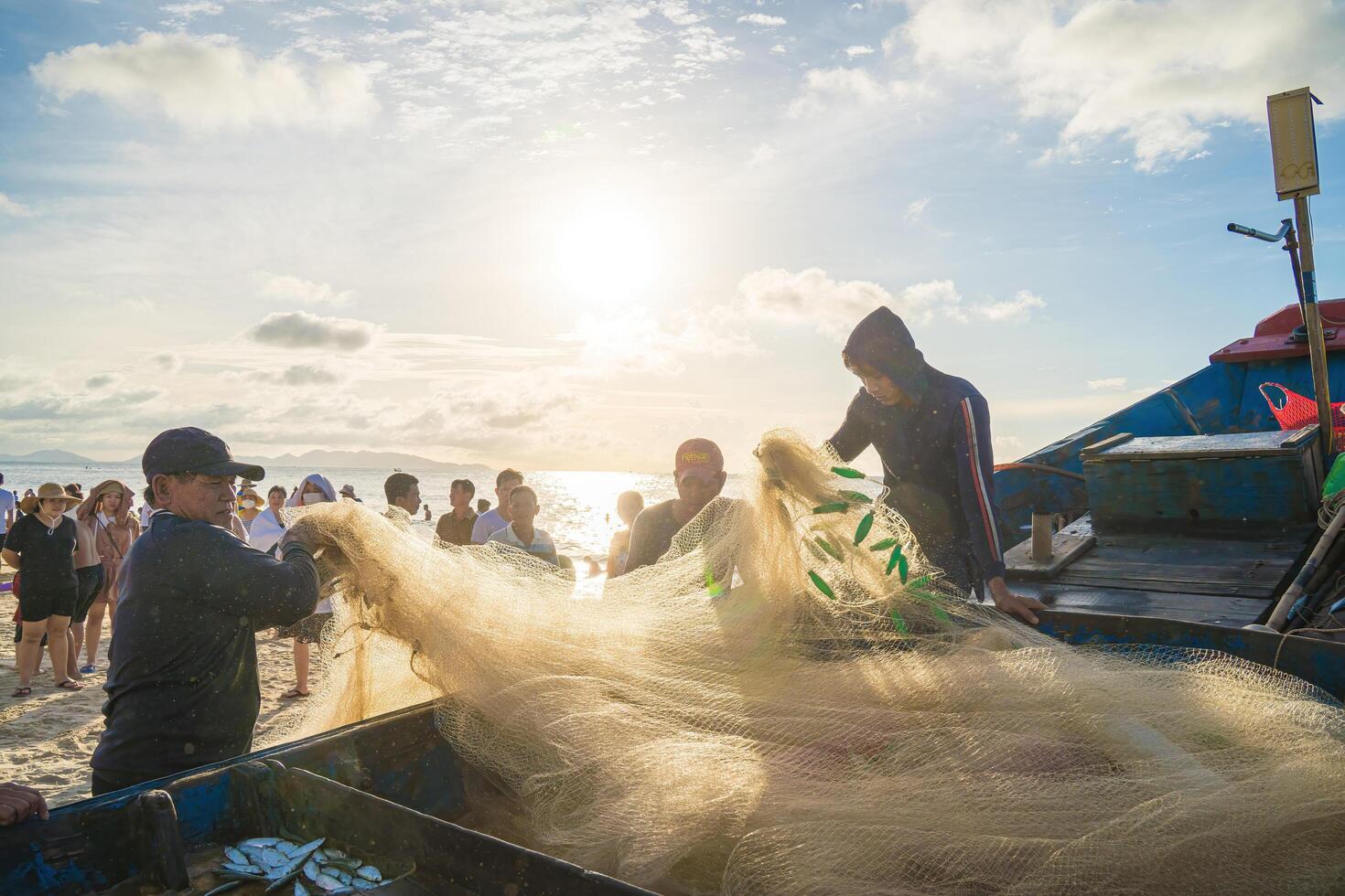 Vung Tau, VIETNAM - AUG 20 2022 Fisherman casting his net at the sunrise or sunset. Traditional fishermen prepare the fishing net. Fishermen on beach at the Fishing. photo