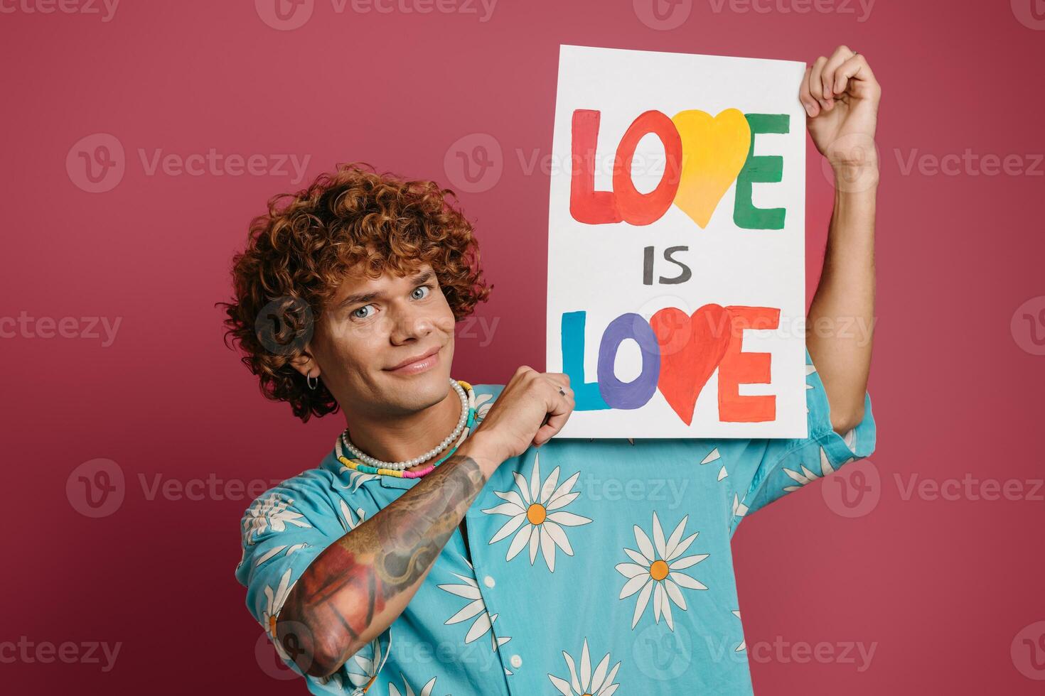 Handsome young man in funky shirt holding colorful banner against red background photo