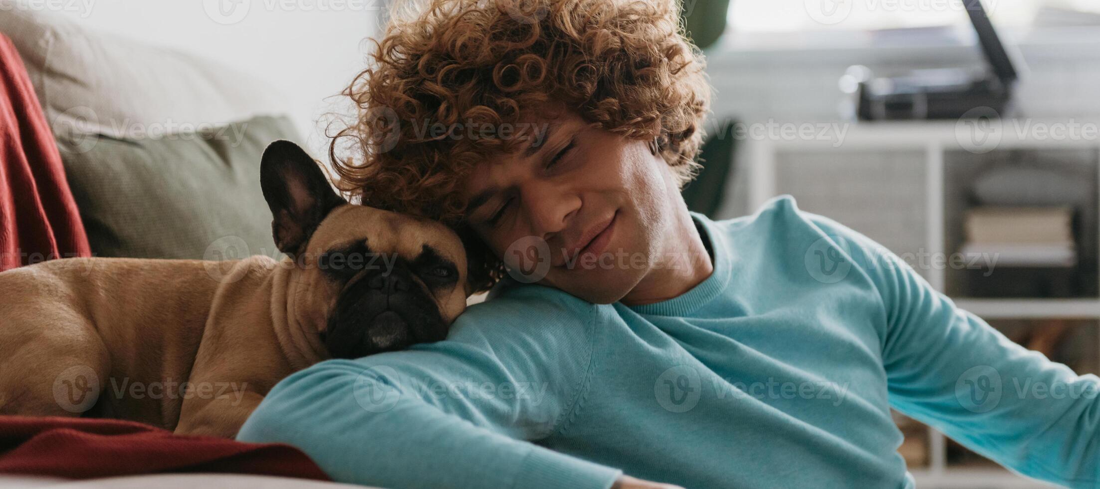 Cute little dog leaning head on shoulder of young handsome man while both napping at home together photo