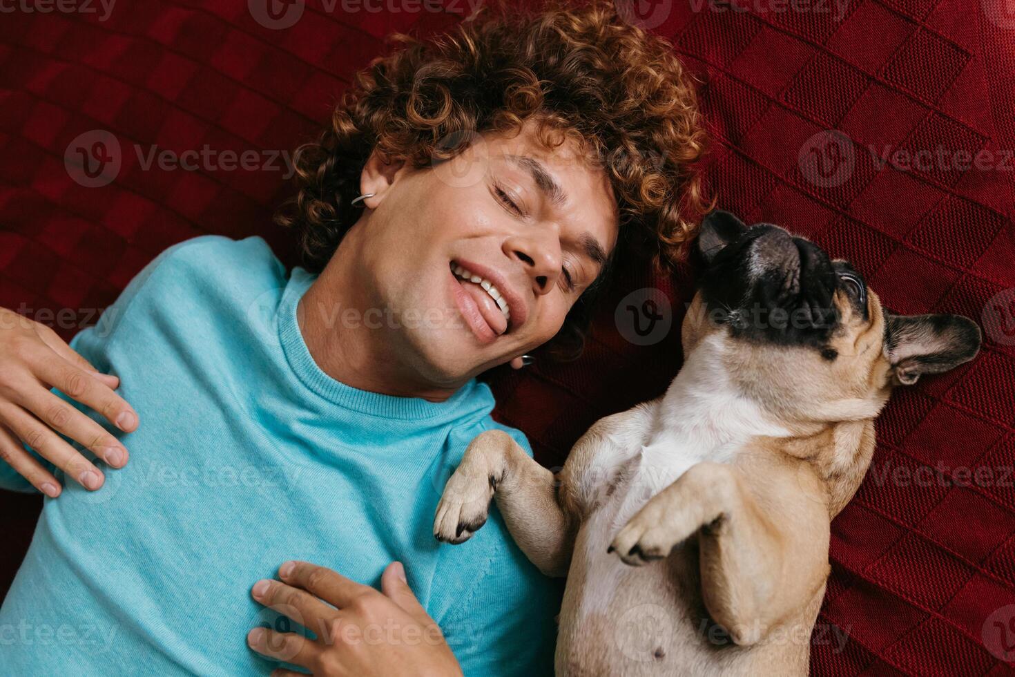 Top view of happy young man having fun with his cute dog while lying on the floor together photo