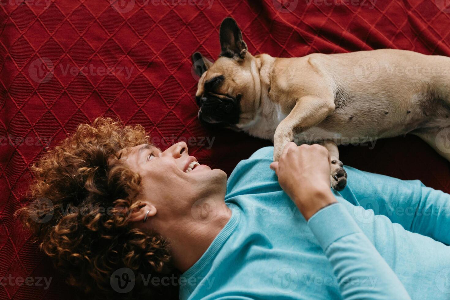 Top view of happy young man petting his cute dog while lying on the floor at home together photo