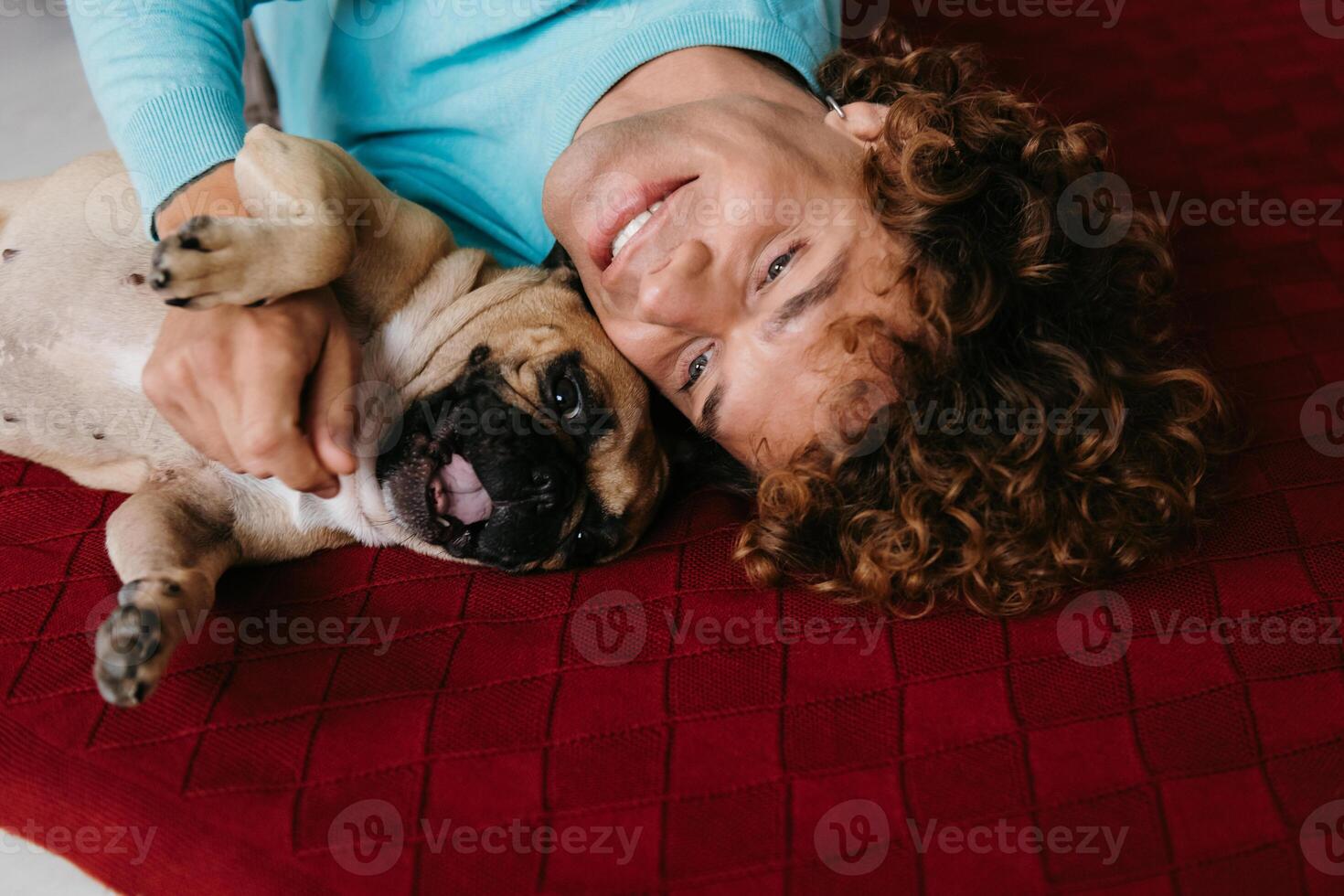Top view of happy young man petting his cute dog while lying on the floor at home together photo