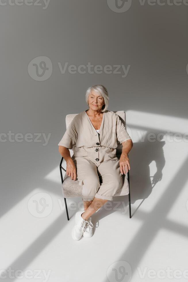 Top view of relaxed gray hair senior woman sitting in comfortable chair and looking calm photo