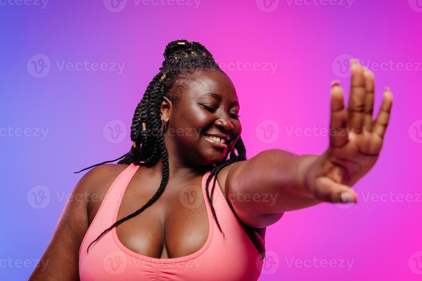 Beautiful African plus size woman in sportswear exercising and smiling on vibrant background photo